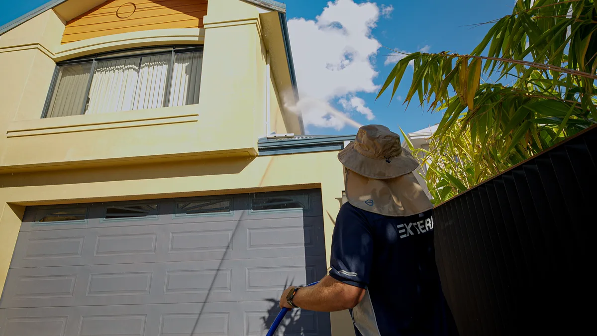 Extera operator soft washing a two-storey Perth house exterior
